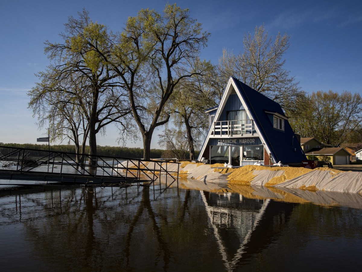 A residential home sits behind a sand barrier as water from the Mississippi River rises.