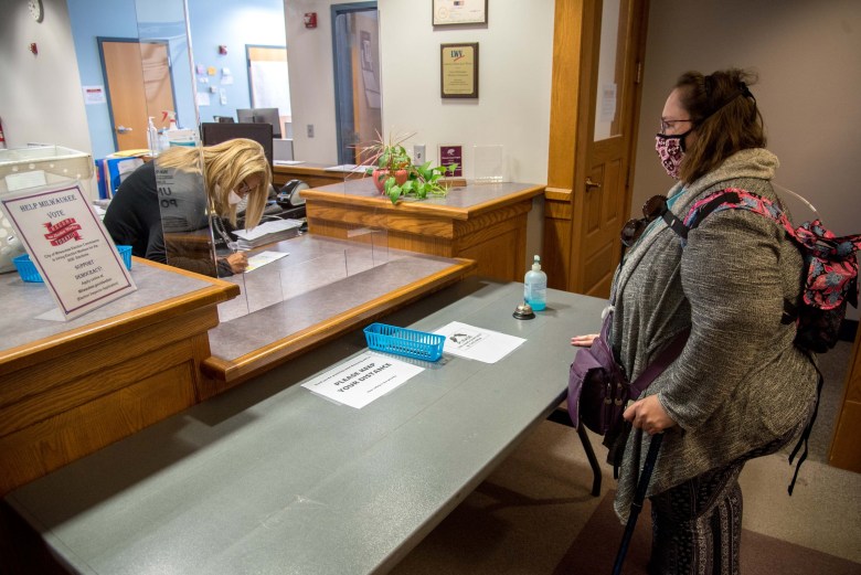 Lee Ann Medina, right, looks on as a Milwaukee Elections Commission employee witnesses her absentee ballot on the day of the election on August 11, 2020.